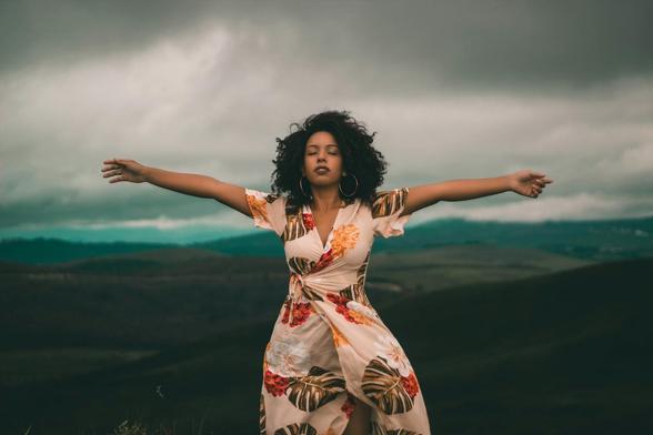 A woman in a flowing dress enjoys peaceful moments in a vast, cloudy landscape. A woman in a flowing dress enjoys peaceful moments in a vast, cloudy landscape.