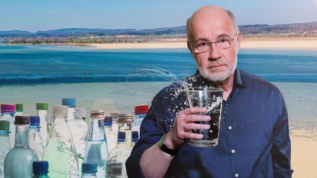Professor Harald Lesch mit Wasserglas vor Bodensee mit Niedrigwasser