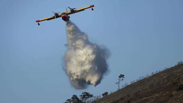 Un avion larguant sa cargaison sur une colline.