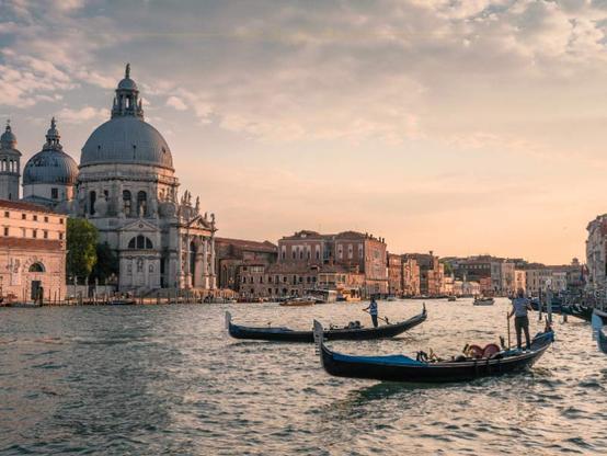 Two gondolas on the Grand Canal in Venice, at sunset. Behind, you can see the cupola of the Academia building
