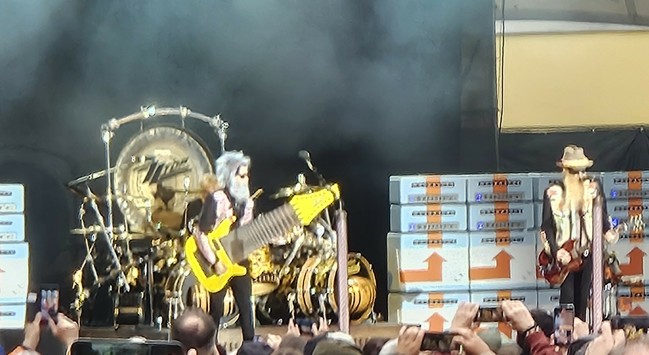 ZZ Top auf der Bühne. Links der gelbe eBass hat einen 3-4 mal so breiten Hals als normale Gitarren. 