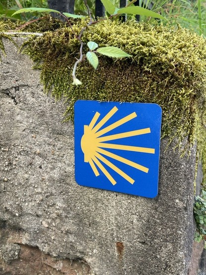 Schild an Mauer mit Zeichen des Jakobsweg.