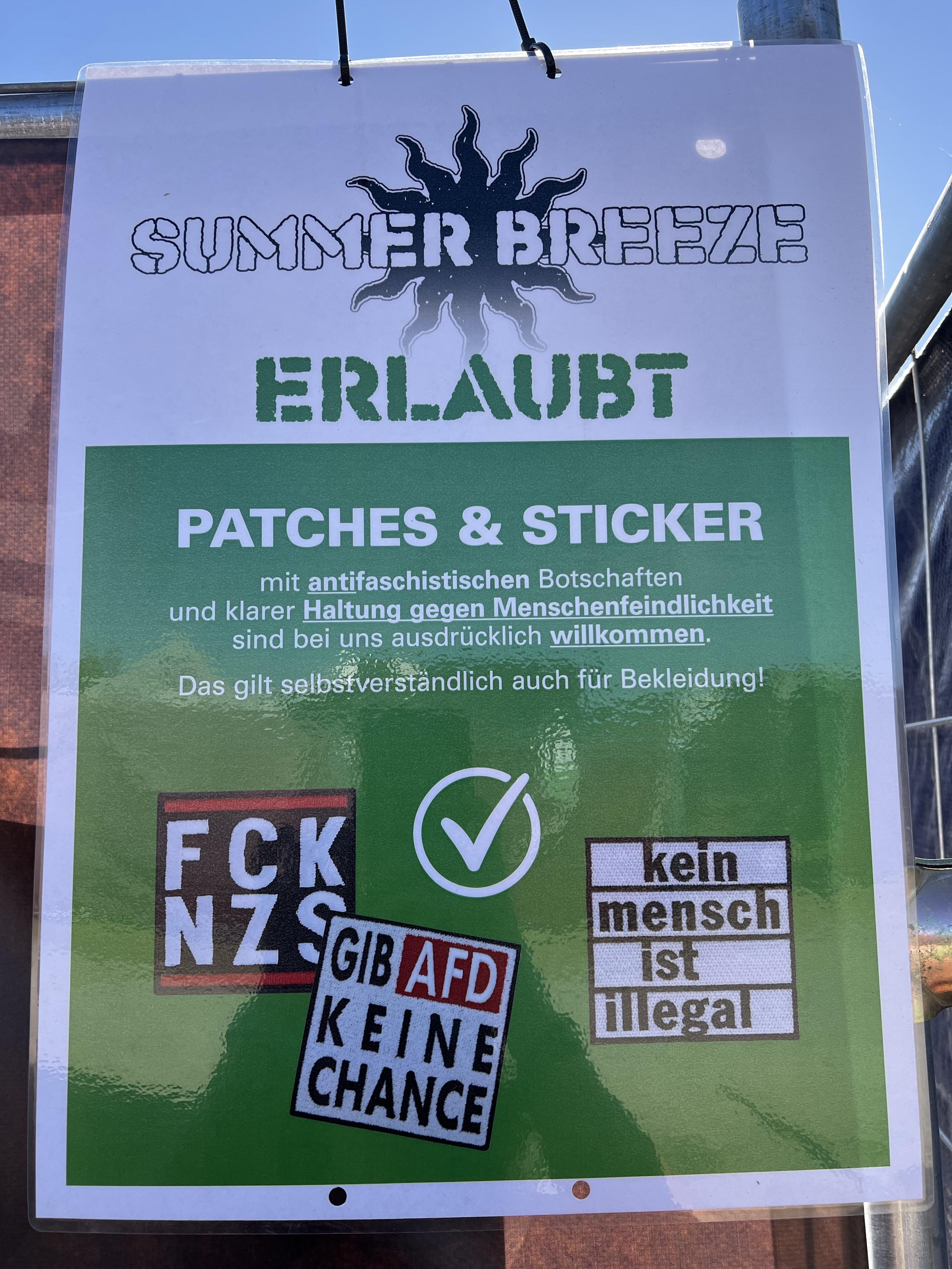 Plakat auf dem Summerbreeze Festival am Einlass mit der Aufschrift:“ERLAUBT ;
PATCHES & STICKER
mit antifaschistischen Botschaften und klarer Haltung gegen Menschenfeindlichkeit sind bei uns ausdrücklich willkommen.
Das gilt selbstverständlich auch für Bekleidung!“